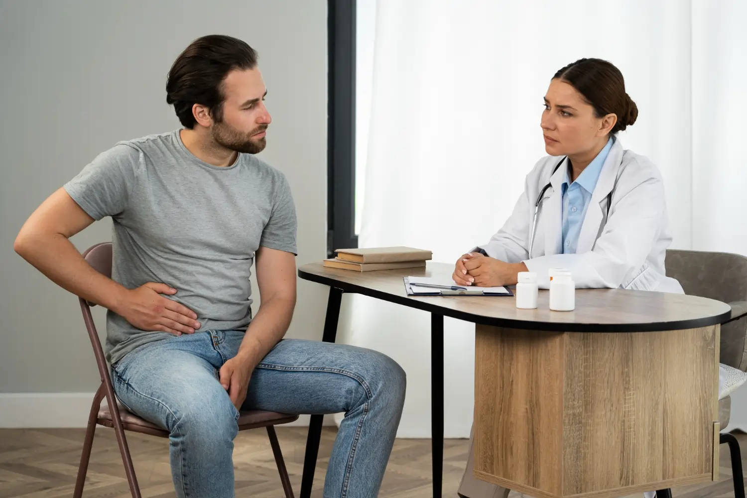 A male holding his kidney to hold the kidney pain while talking to a nephrologist